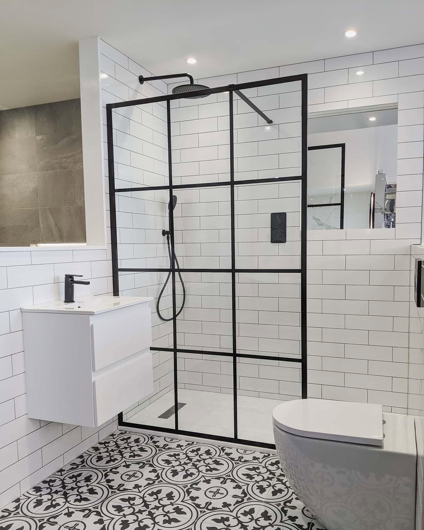 Monochrome shower room with white metro tiles, black framed screen and patterned floor