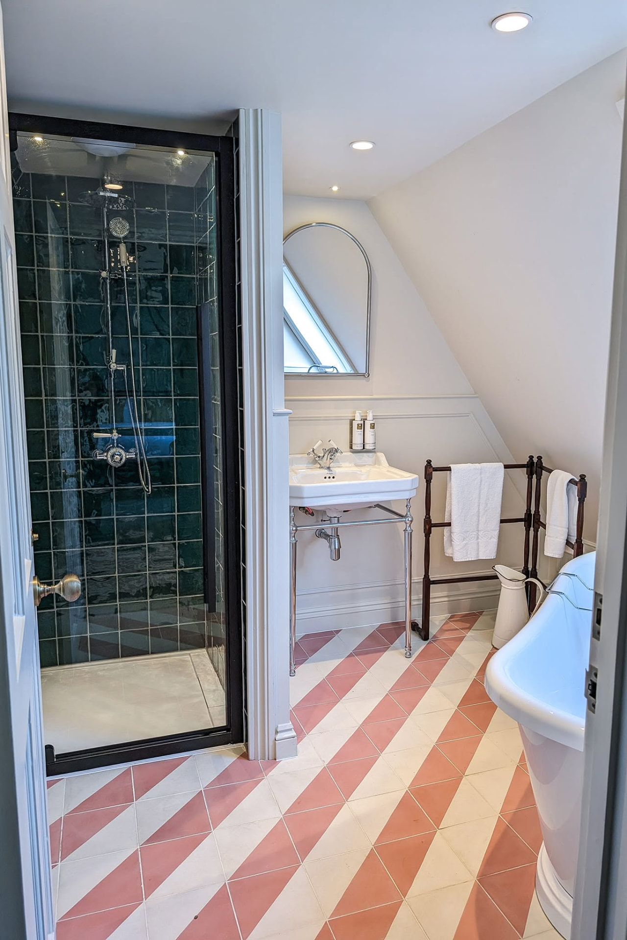 Loft bathroom with green tiled shower, console basin and terracotta striped floor